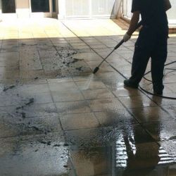 Trabajador realizando llimpieza de suelo con máquina de agua de chorro a presión