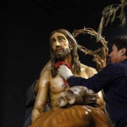 Trabajador realizando limpieza con un trapo en escultura de paso de Semana Santa