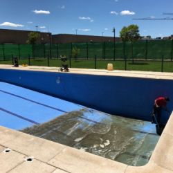 Imagen de trabajador realizando limpieza de interior de piscina vacía