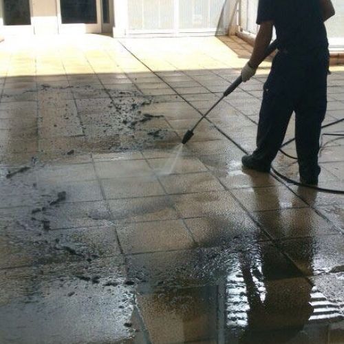 Trabajador realizando llimpieza de suelo con máquina de agua de chorro a presión