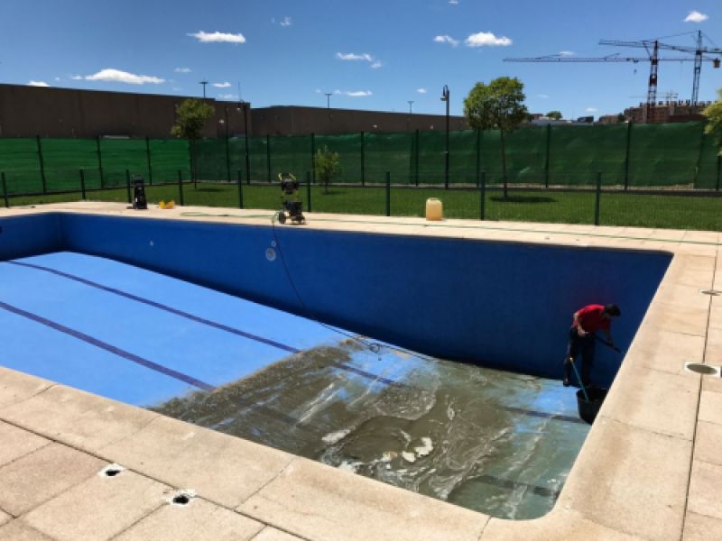 Imagen de trabajador realizando limpieza de interior de piscina vacía